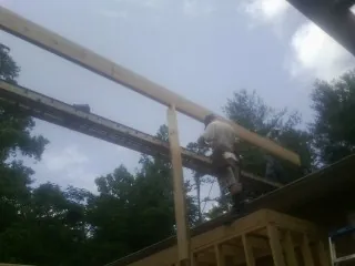 Carpenter setting a ridge beam over a new addition frame — Ice Dam Removal by Roofing Brothers in Roxbury